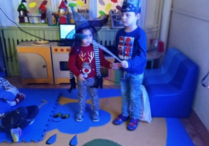 dziewczynka i chłopiec w czapkach czarodziejów wypowiadają zaklęcie